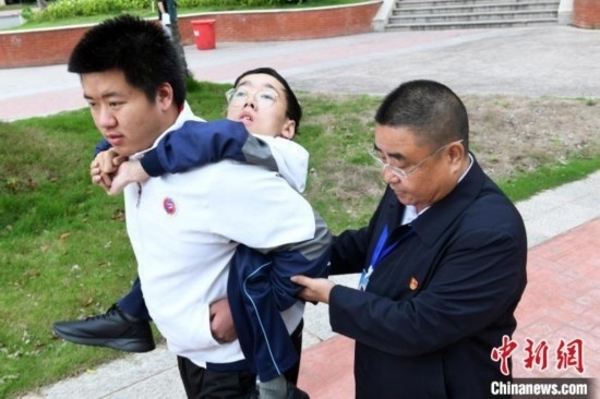 朱金祥背著鐘華強(qiáng)去教室上課的路上，也經(jīng)常碰到值班的校領(lǐng)導(dǎo)和老師前來搭把手。 卓忠偉 攝