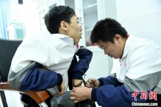 江西省南康中學(xué)北校區(qū)的高三學(xué)生朱金祥(右)正在給鐘華強(qiáng)(左)系好鞋帶。 卓忠偉 攝