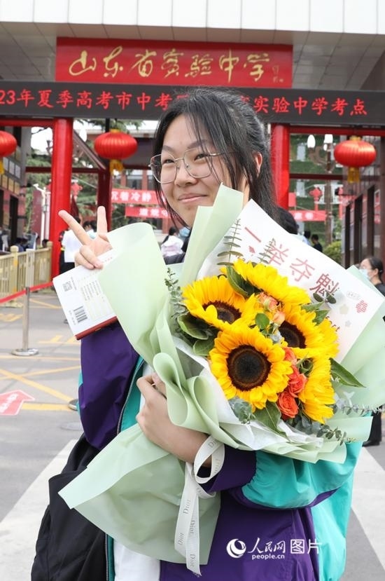 6月7日高考首日，山東67萬考生走進考場，拼搏逐夢。在山東省實驗中學(xué)考點，考生進考場前手捧向日葵花拍照留念，寓意“一舉奪魁”。人民網(wǎng)記者 劉祺攝