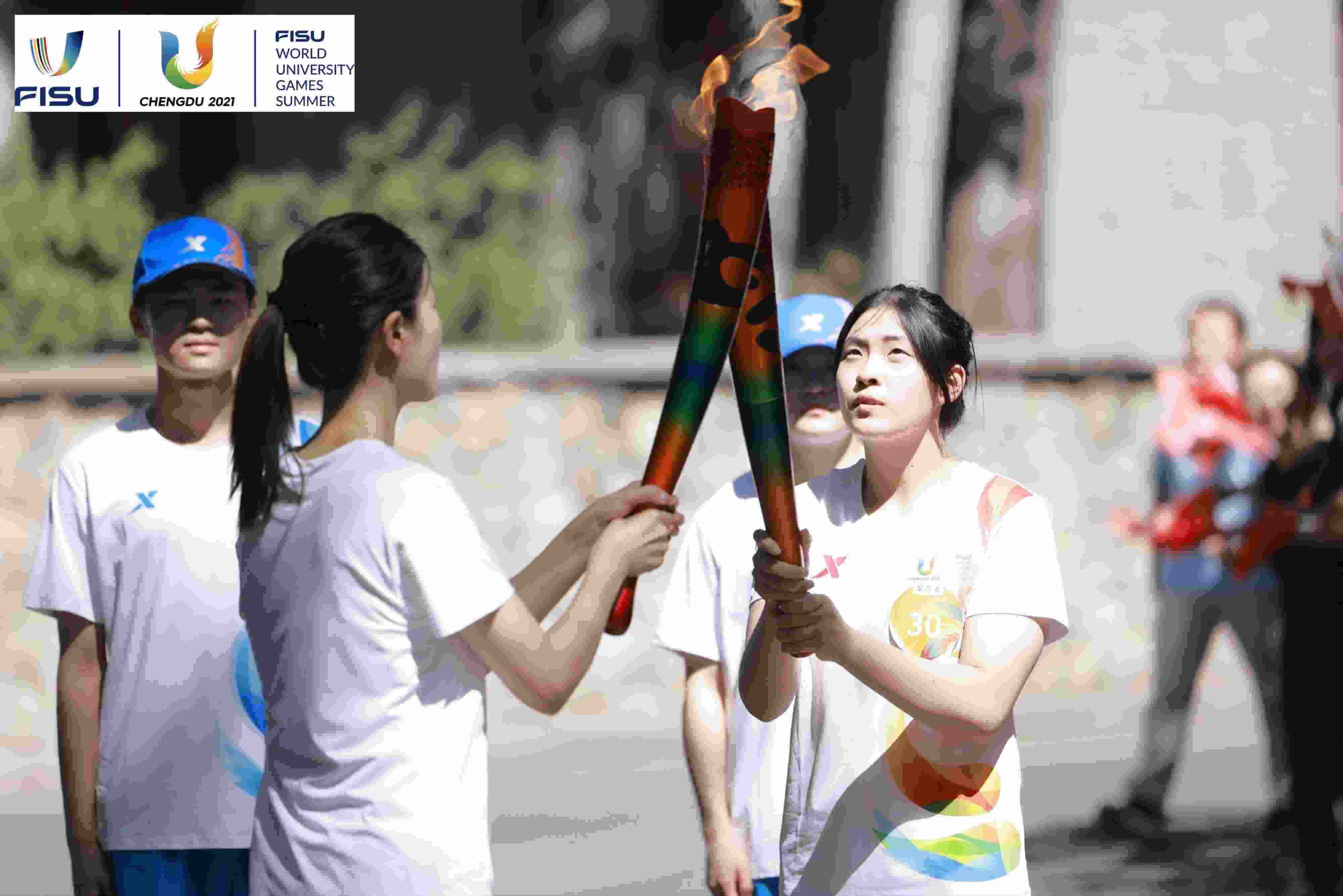 兩名大運會火炬手進行火炬?zhèn)鬟f。 圖片來源：成都大運會執(zhí)委會供圖