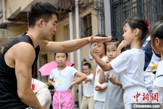 圖為大學(xué)生志愿者在組織孩子們參加體育健身活動。廖光福 攝