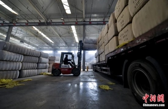 新疆喀什綜合保稅區(qū)，喀什啟路國際貿(mào)易有限公司的倉庫內(nèi)，工人正在裝載從塔吉克斯坦和烏茲別克斯坦進(jìn)口的棉花。劉新攝