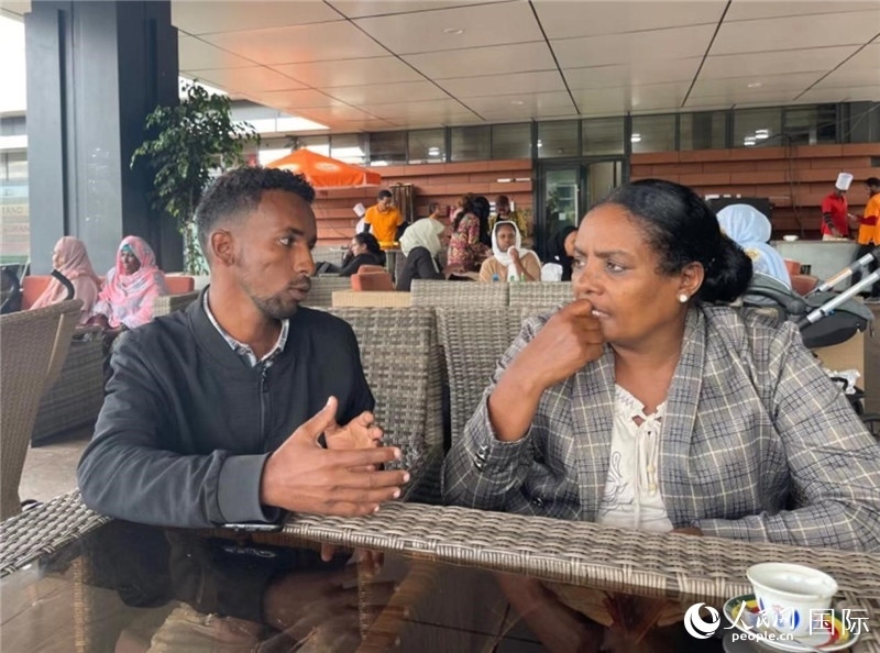 約漢斯（圖左）與德貝拉在友誼廣場(chǎng)咖啡廳交談。人民網(wǎng)記者 趙艷紅攝