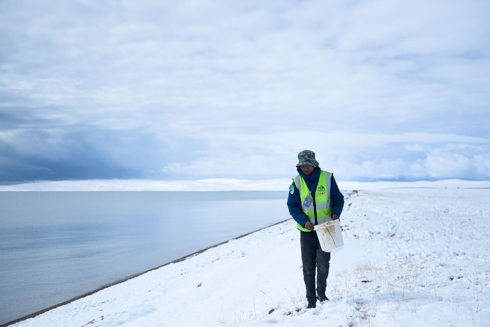 2021年10月20日，在青海省果洛藏族自治州瑪多縣扎陵湖鄉(xiāng)勒那村，三江源國家公園黃河源園區(qū)生態(tài)管護員在扎陵湖邊撿拾垃圾。新華社記者 張龍 攝