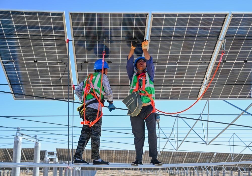2023年7月22日，工人在位于內(nèi)蒙古杭錦旗庫布其沙漠億利生態(tài)示范區(qū)的蒙西基地庫布其200萬千瓦光伏治沙項目工地安裝光伏板。新華社記者 劉磊 攝