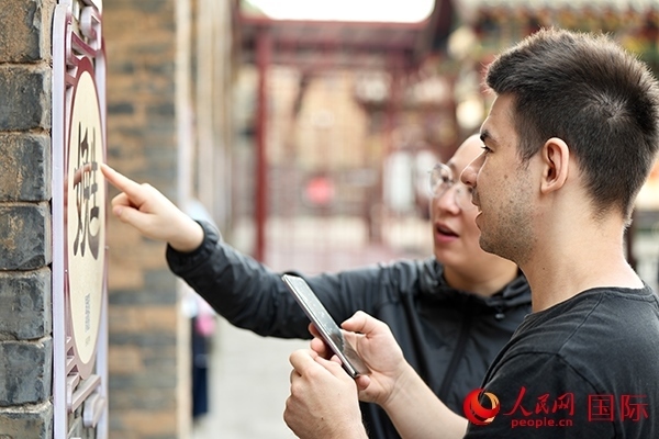 選手安德烈（俄羅斯）在老師指導(dǎo)下學(xué)習(xí)墻壁上張貼的生僻字。人民網(wǎng) 盧鵬宇攝