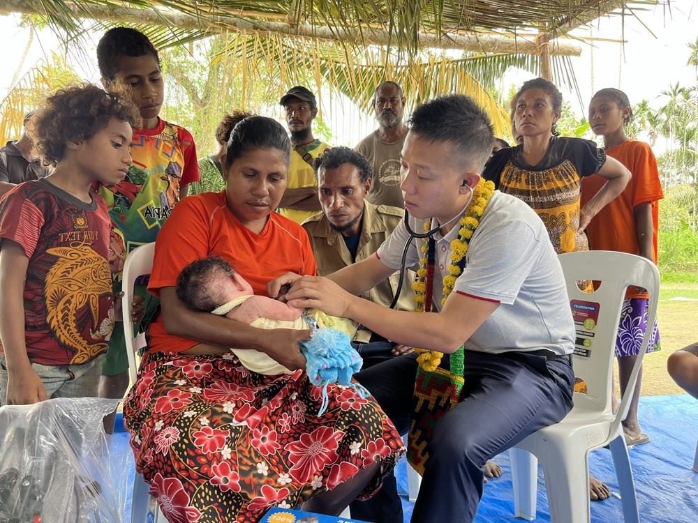 2023年8月5日，在巴布亞新幾內(nèi)亞中央省的一個(gè)村莊里，第12批援巴新中國(guó)醫(yī)療隊(duì)副隊(duì)長(zhǎng)、新生兒科副主任醫(yī)師劉振球?yàn)楫?dāng)?shù)貗雰郝犜\檢查。新華社發(fā)（第12批援巴新中國(guó)醫(yī)療隊(duì)供圖）
