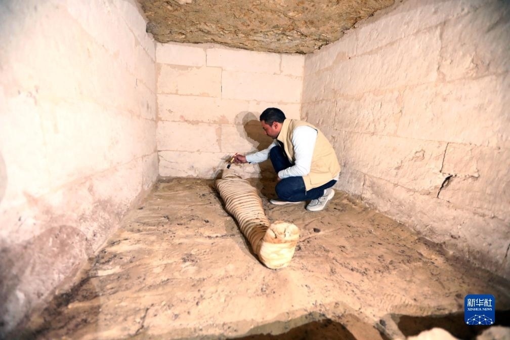 10月15日，在埃及明亞省考古現(xiàn)場(chǎng)，考古人員清理一座石鑿墓中的木乃伊。新華社發(fā)（艾哈邁德·戈馬攝）