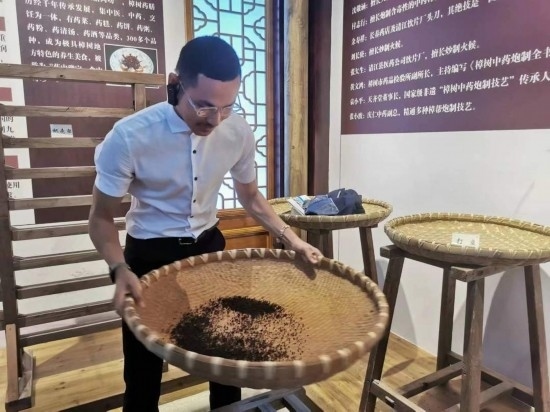 2023“一帶一路”媒體合作論壇聯(lián)合采訪團團員在非遺文化展示館體驗中藥炮制技藝。（本報記者 黃超攝）