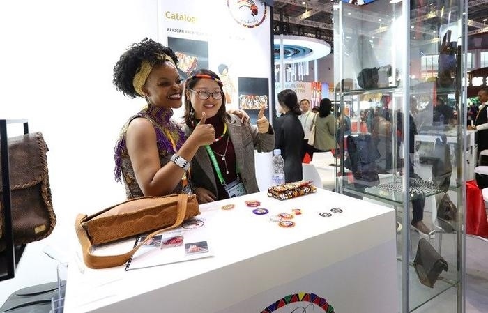 11月6日，一位參觀者（右）在第六屆進博會國家展南非展臺試戴傳統(tǒng)首飾。