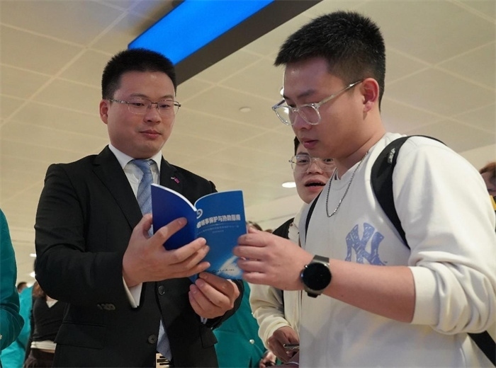 工作人員（左一）在發(fā)放《中國(guó)領(lǐng)事保護(hù)與協(xié)助指南》。 中國(guó)駐迪拜總領(lǐng)事館供圖