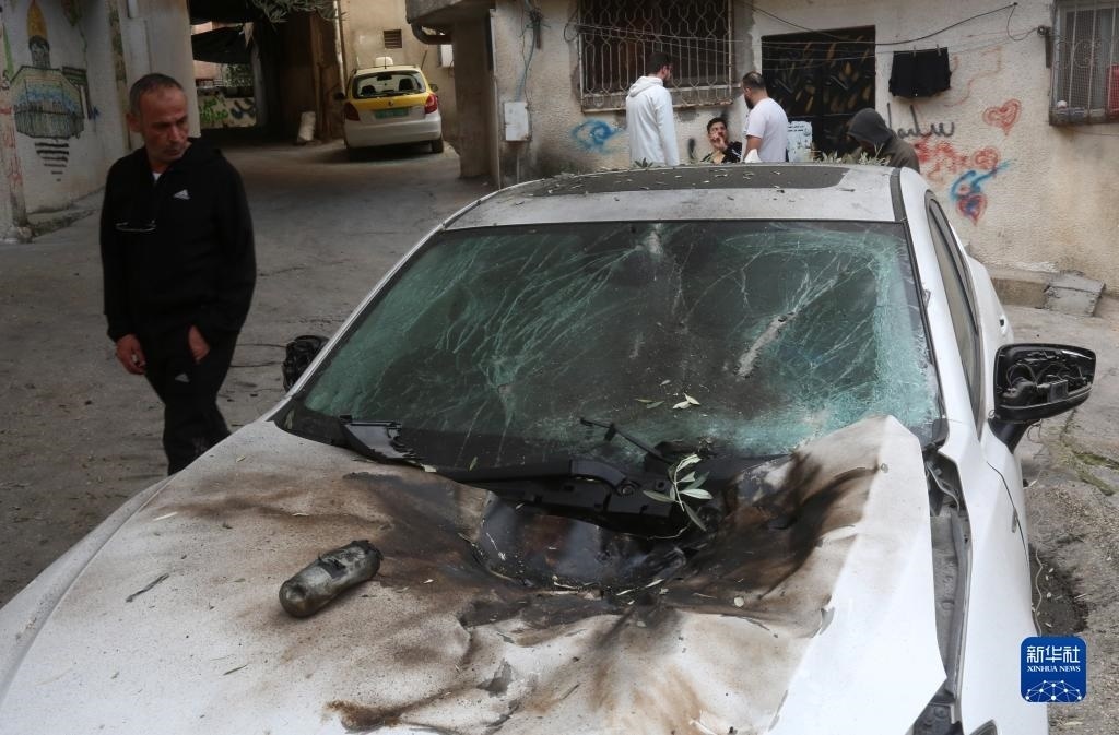 12月17日，在約旦河西岸城市圖勒凱爾姆附近的一處難民營，人們查看在沖突中損毀的車輛。新華社發(fā)（尼達(dá)爾·艾仕塔耶?dāng)z）
