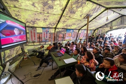 12月22日，在積石山縣大河家鎮(zhèn)大河村安置點(diǎn)，陸軍76集團(tuán)軍某旅搭建的“臨時(shí)學(xué)?！眱?nèi)，小朋友正在看動(dòng)畫片。人民網(wǎng)記者 翁奇羽攝