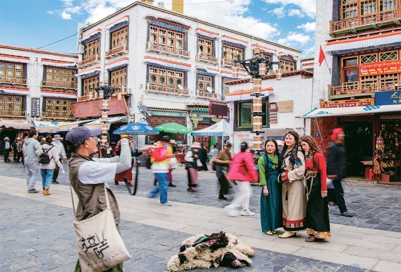 千年八廓街，見證民族團(tuán)結(jié)。2021年7月，習(xí)近平總書記來到位于西藏拉薩老城區(qū)的八廓街，感慨地說：“千年八廓街，是我們各民族建起來的八廓街。各民族文化在這里交流交往交融，我們中華民族的大家庭在這里其樂融融。”圖為2023年6月13日，游客身著藏裝在八廓街拍照留念。 新華社記者 姜帆/攝