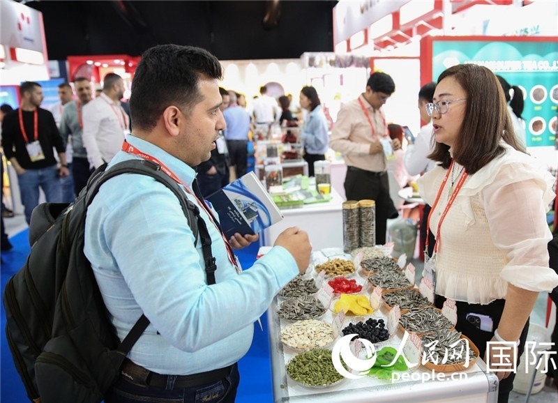 圖為一家中國干果參展企業(yè)代表與采購商洽談。人民網(wǎng) 塔里克·易卜拉欣攝