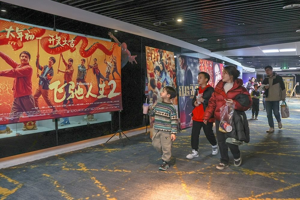 △ 2024年2月16日，在江西贛州一家電影院，觀眾從春節(jié)檔電影的宣傳展板前走過。