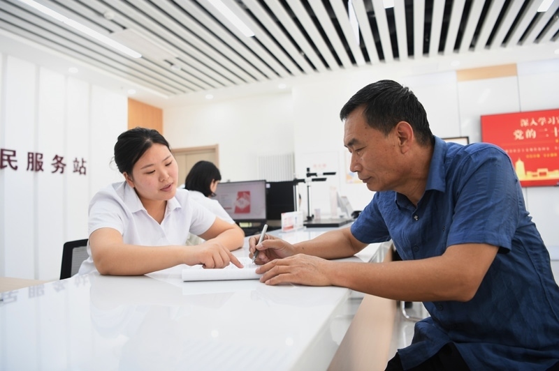 2023年5月23日，河北雄安新區(qū)容東片區(qū)南文營(yíng)社區(qū)居民（右）在社區(qū)便民服務(wù)站辦理業(yè)務(wù)。