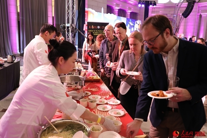 當(dāng)?shù)貢r間3月7日晚，華盛頓聯(lián)合車站廣場舉行駐美使團“使館主廚挑戰(zhàn)賽”。圖為當(dāng)?shù)孛癖娫谥袊古_前體驗中國美食。人民網(wǎng)記者 李志偉攝