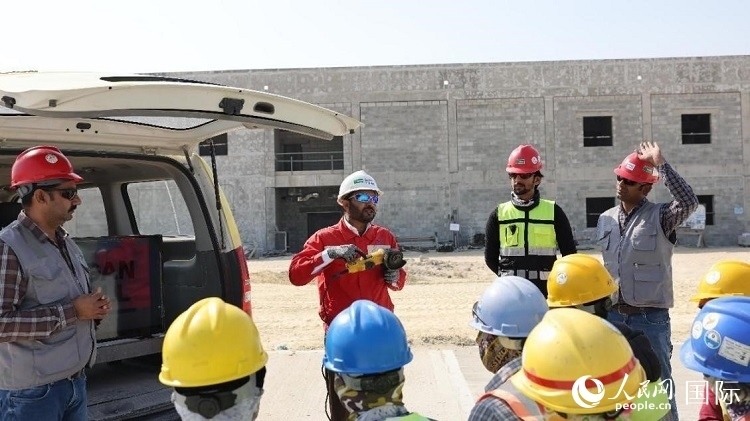 穆薩瓦爾(圖中紅衣人）現(xiàn)場(chǎng)演示工具操作規(guī)范。人民網(wǎng)記者 管克江攝