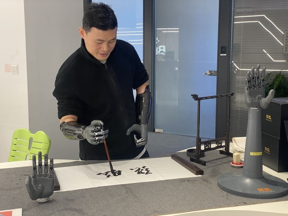 2024年3月29日，在浙江強(qiáng)腦科技有限公司展廳內(nèi)，失去雙手的產(chǎn)品體驗(yàn)官倪敏成依靠智能仿生手寫毛筆字。新華社記者 魏一駿 攝