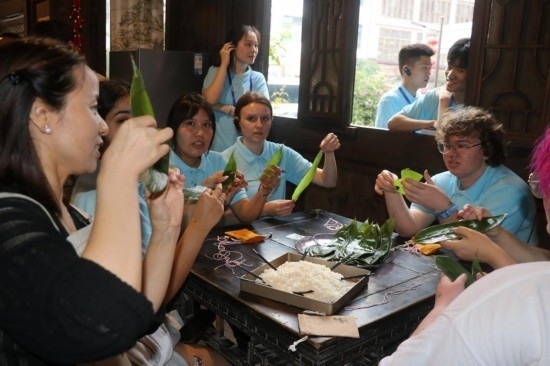 6月9日，美國青年代表在重慶永川松溉古鎮(zhèn)體驗(yàn)包粽子。新華社記者 周思宇 攝