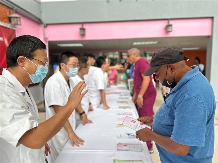 援圭醫(yī)療隊(duì)隊(duì)員們在啟動(dòng)儀式上為當(dāng)?shù)孛癖姺职l(fā)宣傳手冊。中國援助圭亞那醫(yī)療隊(duì)供圖