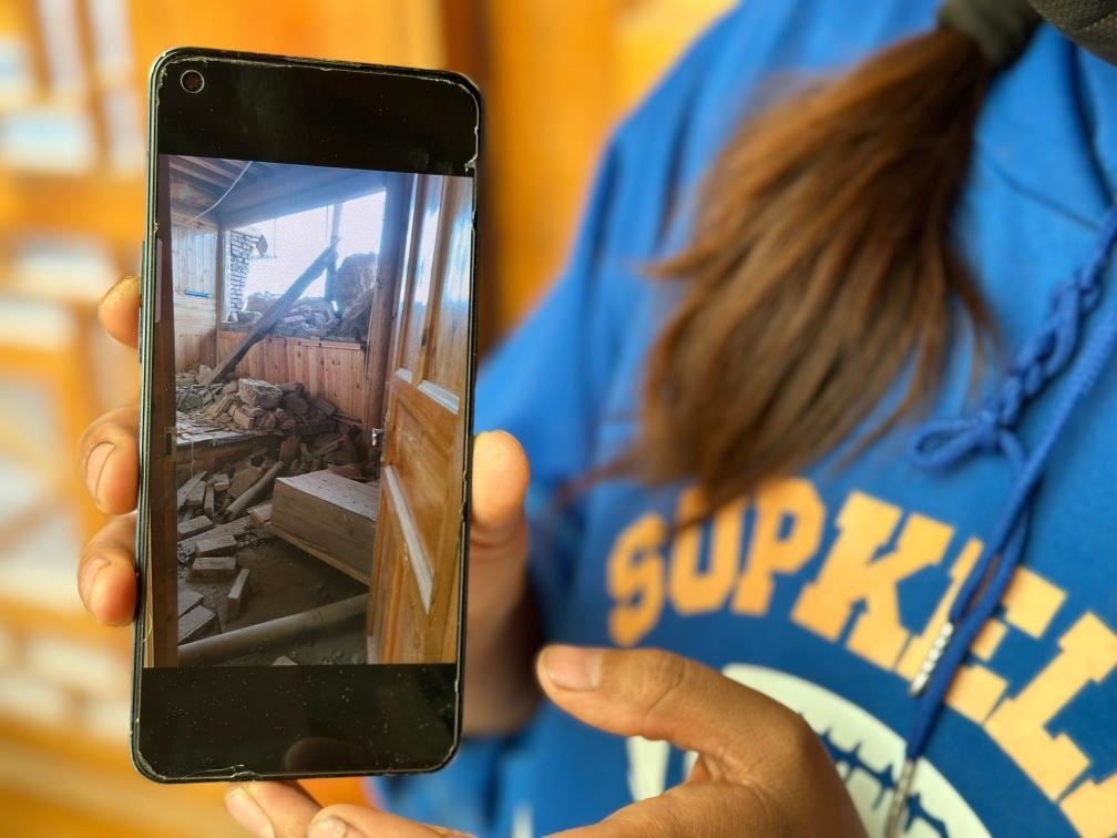 圖為7月17日拉毛東智在手機(jī)上找出地震后房屋受損的照片。新華社記者 張子琪 攝