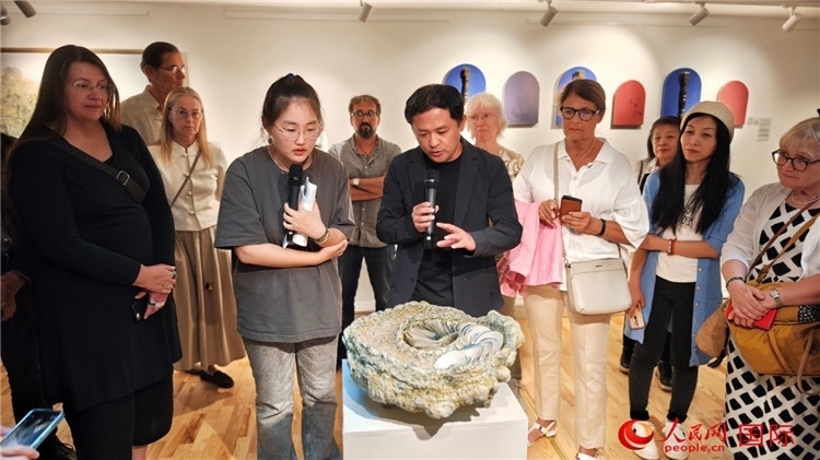 參展人、景德鎮(zhèn)陶瓷大學(xué)設(shè)計藝術(shù)學(xué)院副院長余劍峰（中）向來賓介紹參展作品。人民網(wǎng)記者 殷淼攝
