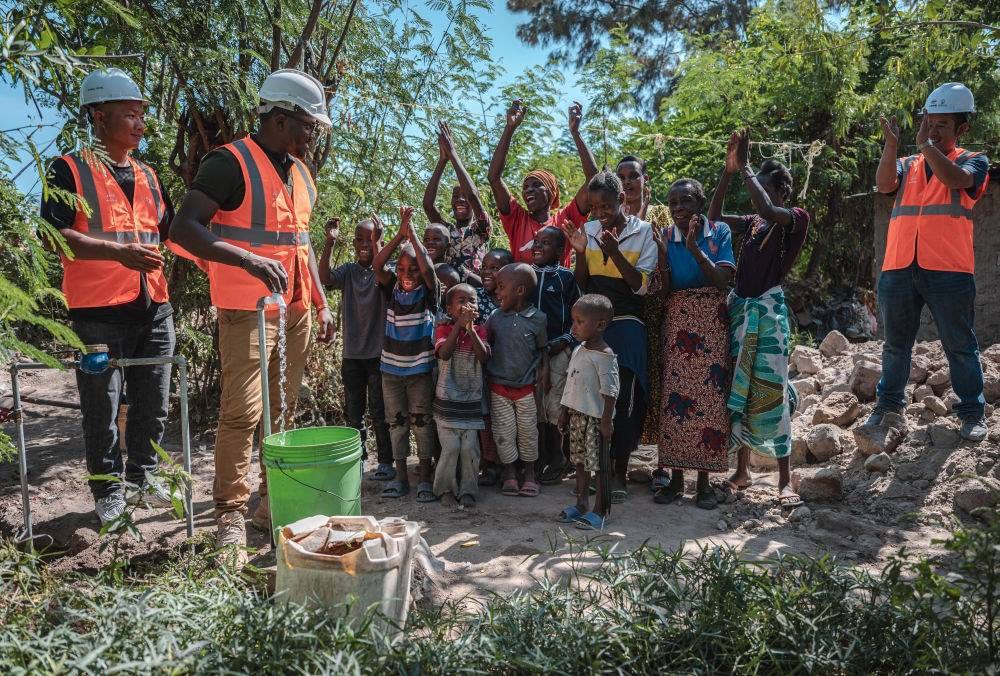 2023年6月13日，在坦桑尼亞姆萬扎省米松圭，工作人員接通水管后贏得當(dāng)?shù)鼐用窆恼茪g呼。新華社記者 王冠森 攝