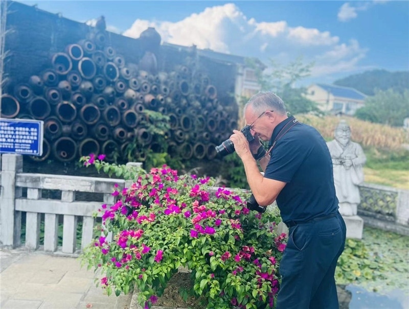 遠(yuǎn)處黔北民居錯(cuò)落有致，近處一只黑色的蝴蝶穿梭于粉紫色三角梅花叢間隙，與俄羅斯“大歐亞”總編輯弗拉基米爾·別列日內(nèi)赫的鏡頭玩起了捉迷藏，“你追我逃，不亦樂乎”。（張亞欣攝）