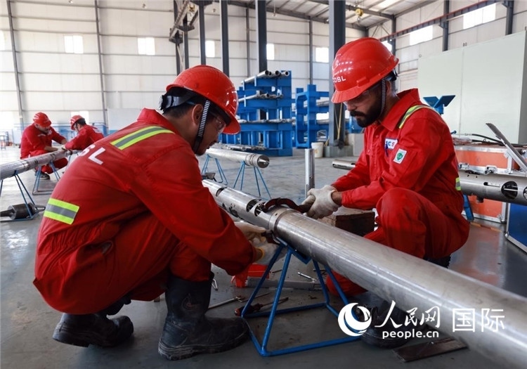 中伊員工共同在檢修鉆井設(shè)備。人民網(wǎng)記者管克江攝