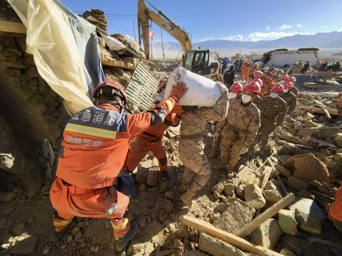 1月11日，定日縣長(zhǎng)所鄉(xiāng)古榮村，應(yīng)急消防等救援人員排隊(duì)接力搶運(yùn)掩埋在倒塌房屋下的群眾財(cái)物。人民日?qǐng)?bào)記者楊翹楚攝