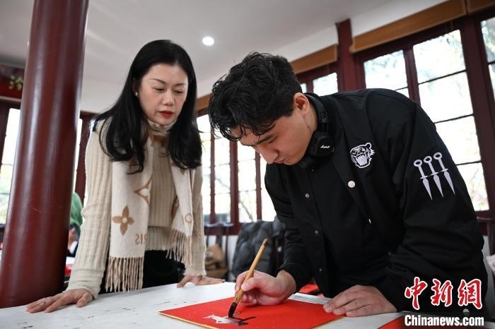 1月20日，外籍留學(xué)生在西泠印社社員李硯指導(dǎo)下寫(xiě)福。當(dāng)日，來(lái)自巴西、馬來(lái)西亞、加納、哈薩克斯坦的外籍留學(xué)生在浙江杭州西泠印社體驗(yàn)福貼、春聯(lián)和篆刻，感受古老的中國(guó)傳統(tǒng)文化。中新社記者 王剛 攝