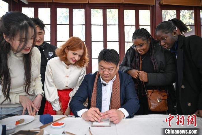1月20日，篆刻家王臻向外籍留學(xué)生展示篆刻印章。當(dāng)日，來(lái)自巴西、馬來(lái)西亞、加納、哈薩克斯坦的外籍留學(xué)生在浙江杭州西泠印社體驗(yàn)福貼、春聯(lián)和篆刻，感受古老的中國(guó)傳統(tǒng)文化。中新社記者 王剛 攝