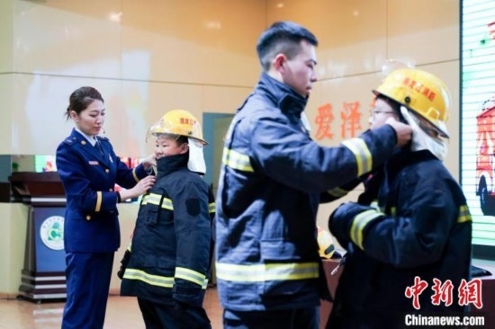 圖為學生們現(xiàn)場穿戴消防頭盔和戰(zhàn)斗服。中新社記者 趙宇航 攝