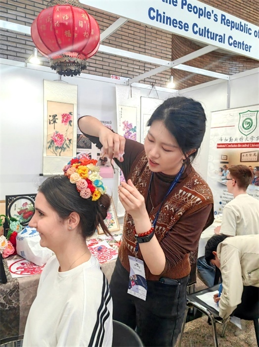 展覽正值羅馬尼亞迎春花節(jié)，國際中文教師志愿者潘婧穎向游客們介紹了國家非物質(zhì)文化遺產(chǎn)——福建泉州的簪花文化。布加勒斯特大學(xué)孔子學(xué)院供圖。