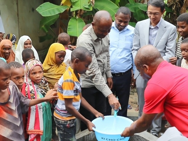 在日前舉行的安全供水工程揭牌儀式上，當(dāng)?shù)匦∨笥言诠┧c接水。 施亮攝
