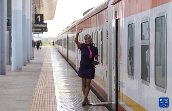 5月31日，在蒙內(nèi)鐵路內(nèi)羅畢站，一名乘務(wù)員在即將開往蒙巴薩的E2次列車旁等候乘客。新華社記者 李亞輝 攝